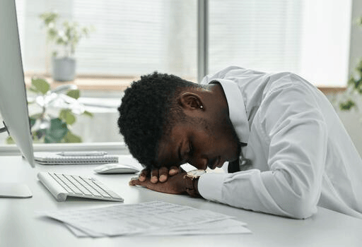Sleep Deprivation and Your Health: Effects of Lack of Sleep + How to Sleep Better Black professional struggling to concentrate due to effects of lack of sleep.